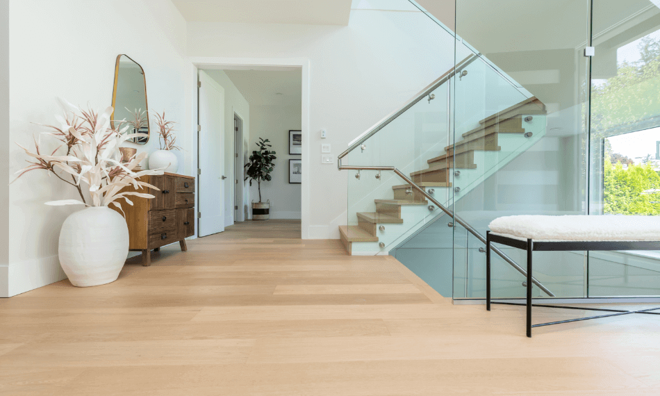 A glass staircase and beige hardwood flooring.